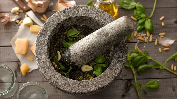 Mortar and pestle with herbs on a wooden surface